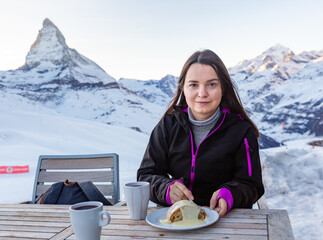 Woman enjoying fragrant mulled wine and slice of apple strudel topped with vanilla sauce in winter...