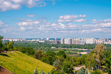 Beautiful cityscape with river viewed from park hill on sunny day against cloudy sky, Picturesque view of city skyline