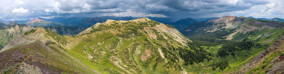 Fototapeta premium Peeler Peak - A panoramic Summer view of Peeler Peak of Elk Mountains, with dark storm clouds hovering over Mount Crested Butte in background. Crested Butte, Colorado, USA. 
