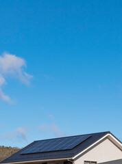 太陽光発電。太陽光パネルが設置された住宅の屋根と快晴の青空。