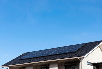 太陽光発電。太陽光パネルが設置された住宅の屋根と快晴の青空。