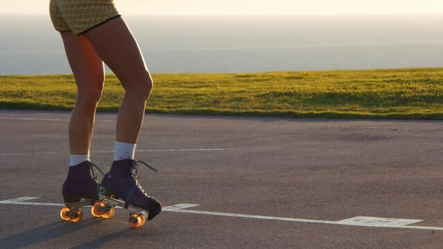 Summer outdoor sports activity concept. Beautiful, cheerful woman riding on roller skates at playground with scenic ocean view in the background. High quality 4k footage