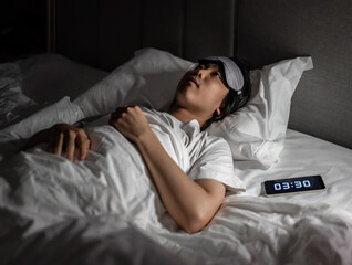 Young man suffering from insomnia lying on the bed with eye stared