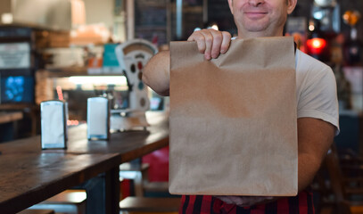 Restaurant employee holding paper take out bag with customer food order