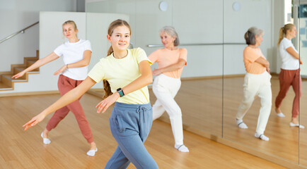 Fototapeta na wymiar Young positive teenager girl dancing during group class in dance center