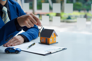 The house sales representative holds the keys and the car with paperwork. home loan Pen insurance...