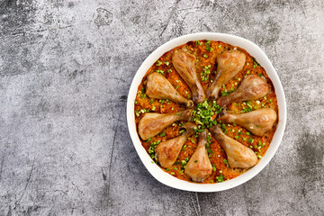 Oven Baked Chicken drumsticks and Rice with in a white baking dish on a dark grey background. Top view, flat lay