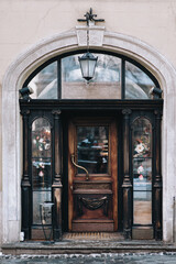 A huge old vintage carved brown door with glass inserts on the facade of the building. Ancient European architecture.