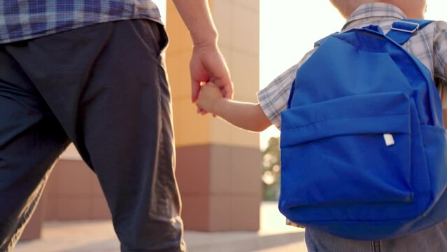 A schoolboy with a school backpack goes to school with his dad. Happy family. Education for children. Happy son, a boy with a school backpack hurries to school. Family, Kid, Boy, dad go home