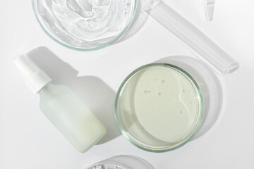 top view of cosmetic fluid in glass bottle and petri dish and test tube on a laboratory table. lab research on skin care cosmetic ingredients and product safety.