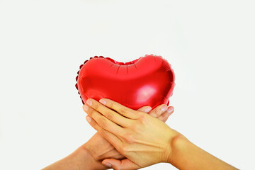 Red balloon heart in middle the hands. Representation of heart disease.