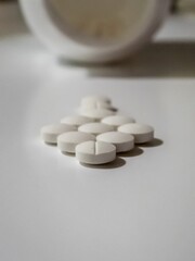 White Tablets Of Medicine And A Bottle In The Background