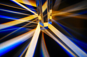 Closeup of group of reflective clear triangular prisms dispersing and spreading beam of light in to...