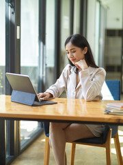 Businesswoman remote working in the cafe, working on tablet.