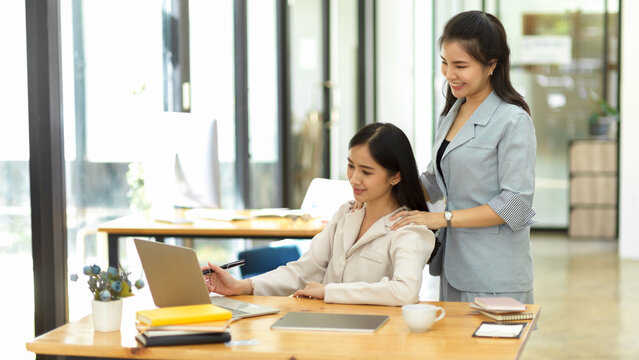 A Supportive Female Colleague Helping Her Colleague Friend On The Project