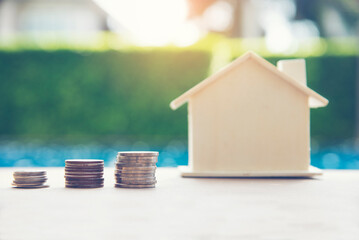 Women hand holds a coin in a piggy bank for future home purchases. Save money. Economic concept