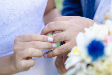 unrecognizable bride putting wedding ring on groom, close up