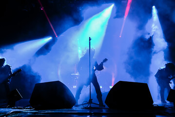 silhouette of a singer vocalist and guitar player performing at a concert in the fog. Dark...