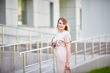 caucasian young woman in a beautiful dress on the street looks at the camera and smiles.