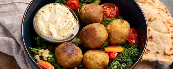 Falafel with hummus on dark background.