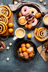Table with various cookies, donuts, cakes and coffe cups