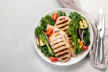 Grilled chicken with vegetables on light background.