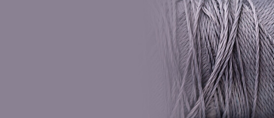 Purple thread, texture, macro, close-up, copy space. A bright banner with a silk thread pattern. Sewing minimalistic concept. Beautiful abstract background. A spool with threads