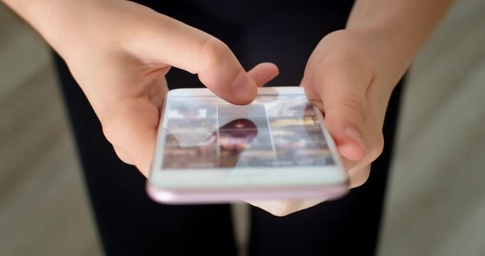 Close-up shot of hands using smartphone surfing in internet. Scrolling news feed with pictures or photo gallery choosing content for social media or instagram. Mobile gadget and technology concept