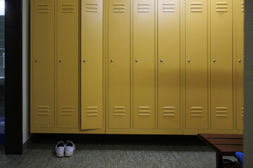 yellow lockers and a pair of shoes stand in a locker room