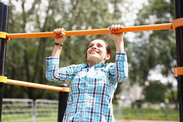 Obraz premium Woman hanging on horizontal bar and smiling