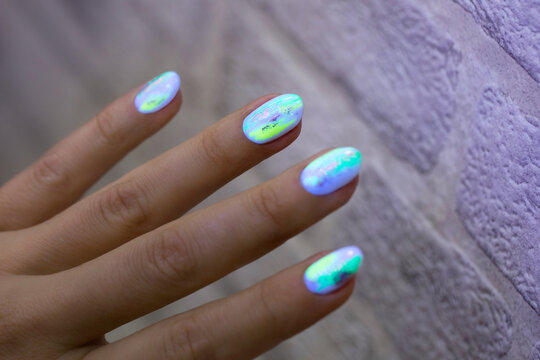 A girl's hand with a bright neon manicure that glows in the dark. Fashionable manicure in a beauty salon for a summer holiday. 