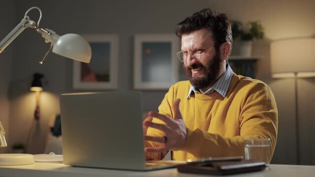 Man disgust, abomination, FU, auch emotion. Bearded man in glasses looks at computer screen and winces at what he sees in laptop