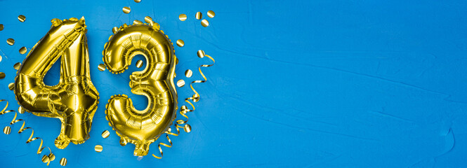 golden foil balloon number forty three. Birthday or anniversary card with the inscription 43. blue concrete background. Anniversary celebration. Banner.