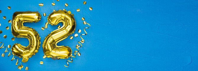 number fifty two gold foil balloon. Birthday or anniversary card with the inscription 52. blue concrete background. Anniversary celebration. Banner.