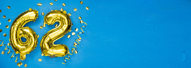 golden foil balloon number sixty two. Birthday or anniversary card with the inscription 62. blue concrete background. Anniversary celebration. Banner.