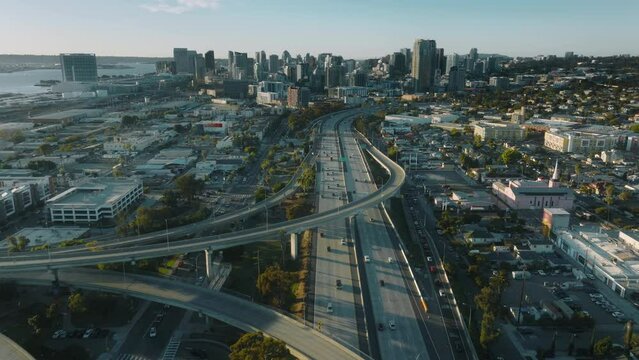 Cinematic aerial downtown San Diego at sunset. Drone flying above busy highway towards high modern buildings on sunny summer day. American city background, residential buildings, California USA 4K