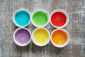 Cans of paint. Rainbow. Multicolored colours. Blue, yellow, orange, green. wooden background