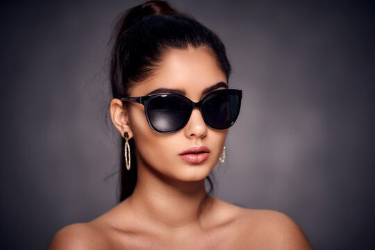 fashion portrait of beautiful Indian woman who wearing sunglasses and golden earrings. Asian glamour