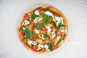 vegetarian pizza with cheese tomatoes and basil with pesto sauce on a white background
