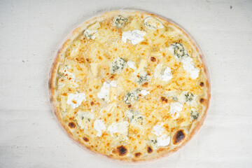 four cheese pizza on a round board on a white background
