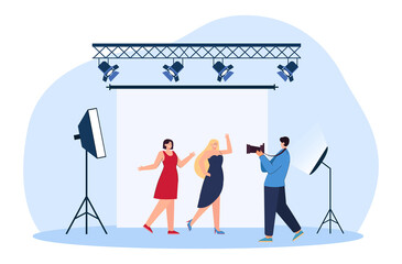 Photographer taking photos of models flat vector illustration. Women in dresses posing for camera on backdrop in professional studio with light. Photography, shooting concept