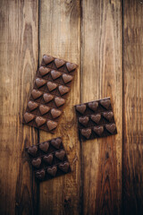 Delicious sweet pieces chocolate on wooden background shape of heart