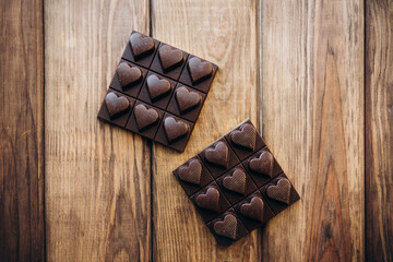 Delicious sweet pieces chocolate on wooden background shape of heart