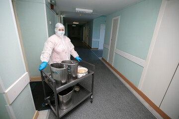 A nurse in a protective suit distributes food during a coronavirus infection. Hospital meals.