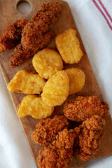 Tasty Fastfood: Chicken Nuggets, Wings and Tenders on a rustic wooden board, top view. Overhead, from above, flat lay.
