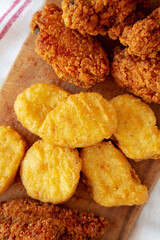 Tasty Fastfood: Chicken Nuggets, Wings and Tenders on a rustic wooden board, top view. Overhead, from above, flat lay.