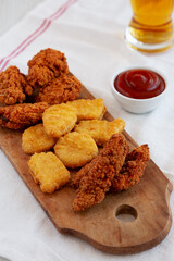 Tasty Fastfood: Chicken Nuggets, Wings and Tenders with Ketchup and Beer, side view.