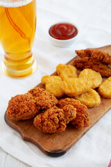Tasty Fastfood: Chicken Nuggets, Wings and Tenders with Ketchup and Beer, side view.