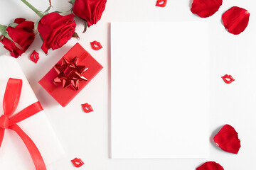Postcard mockup with empty white template for design and copy space with red flowers and gifts, flat lay. Congratulations and greetings list.