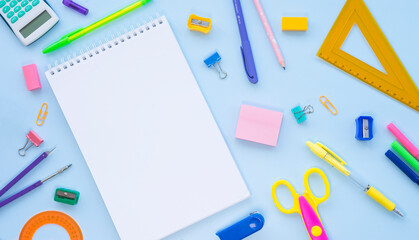 Assorted stationery and white notepad on blue background